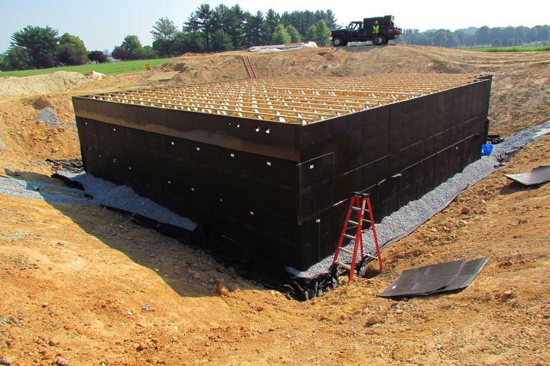 Poured concrete basement walls with dark damp-proofing coating on site
